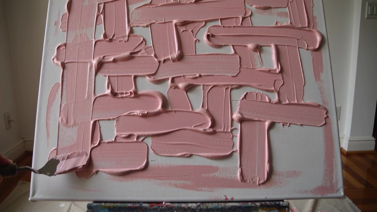 Entering hand with dark sleeve applying palette knife across canvas on easel, building pink impasto
