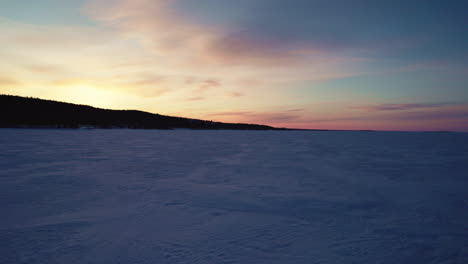 Flying-drone-above-a-frozen-lake-in-canada-at-golden-hour