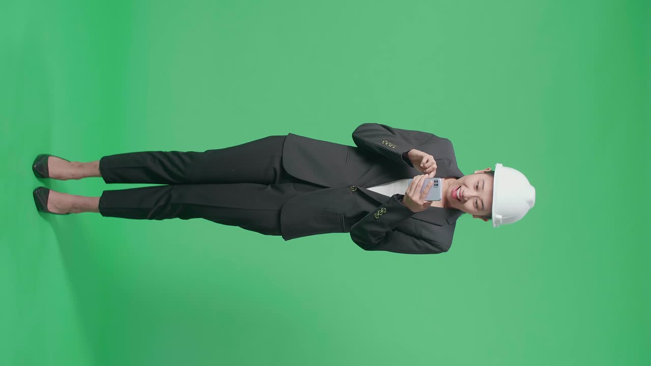 Full Body Of Happy Asian Female Engineer Celebrating While Using Smartphone In The Green Screen Studio