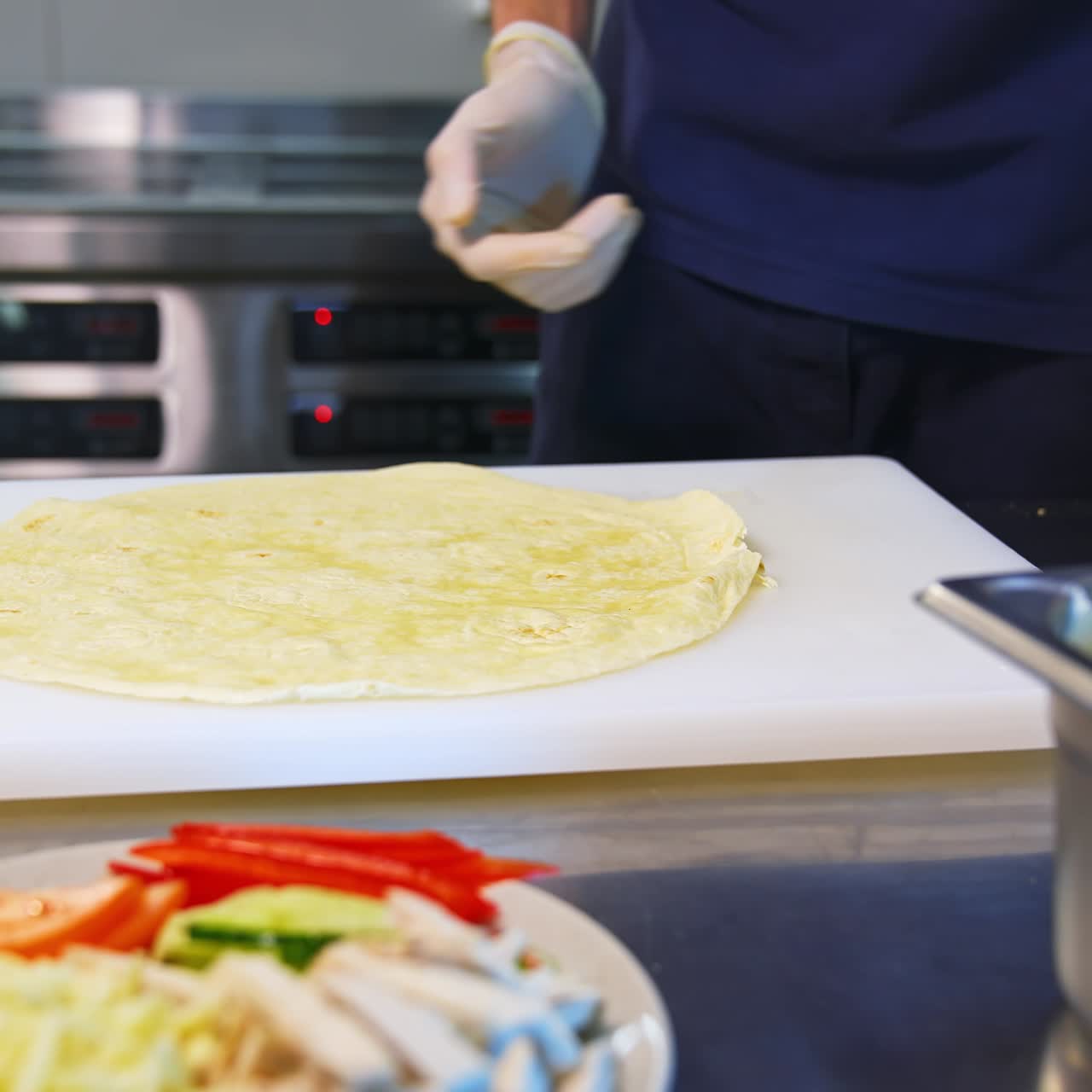 Pita on a table. Man`s hands put white souce on a top. Place with ingredients stand at side. Tasty junk food