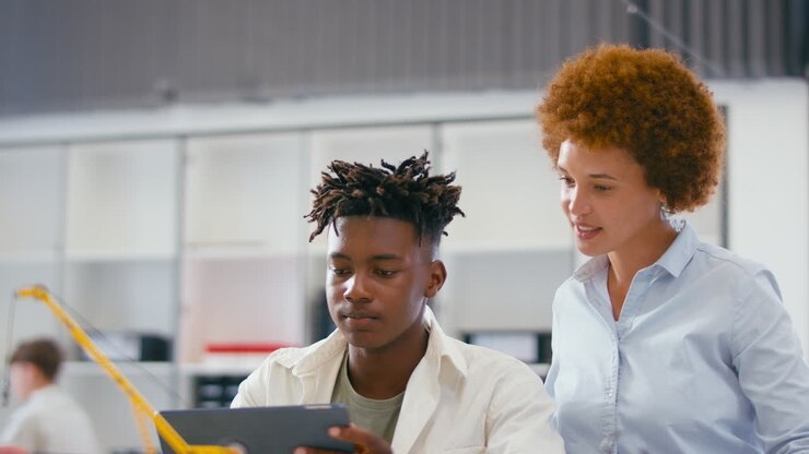 Female Teacher With Male High School Student Using Digital Tablet In STEM Class