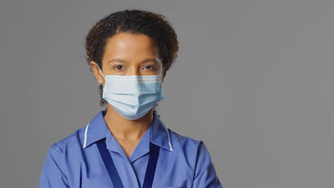 studio portrait of female nurse wearing uniform and face mask