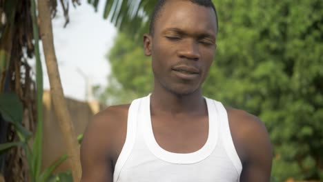 a close shot of an african mans face as he wipes the sweat from his brow after working in the hot african sun and digging in his garden