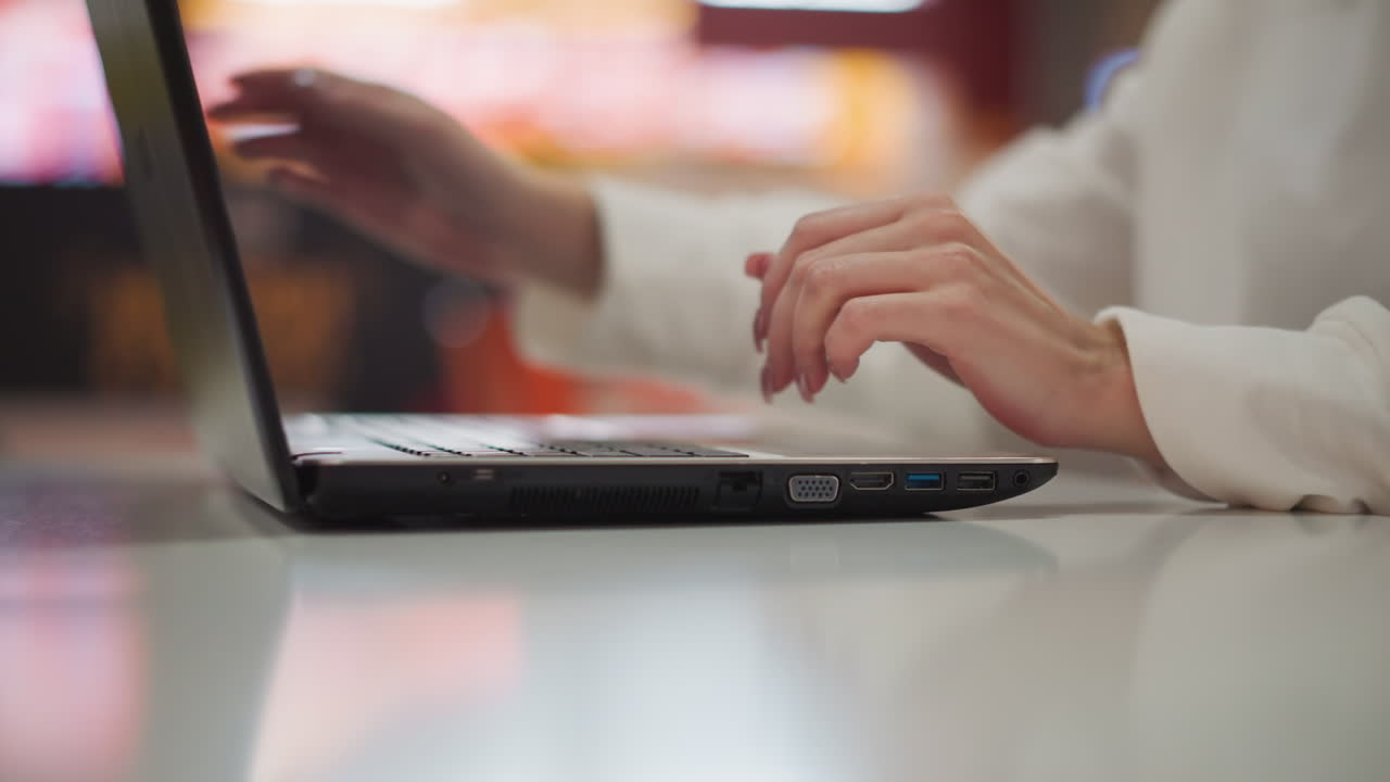 primer plano de una computadora portátil cerrada por una persona en un entorno de centro comercial moderno, con luces de fondo borrosas vibrantes y atmósfera urbana