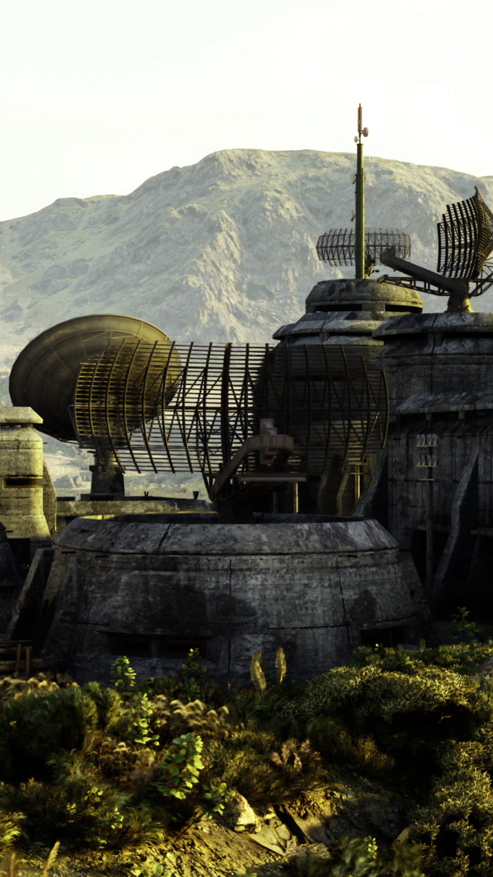 Buildings and antennas in a remote area surrounded by mountains and vegetation