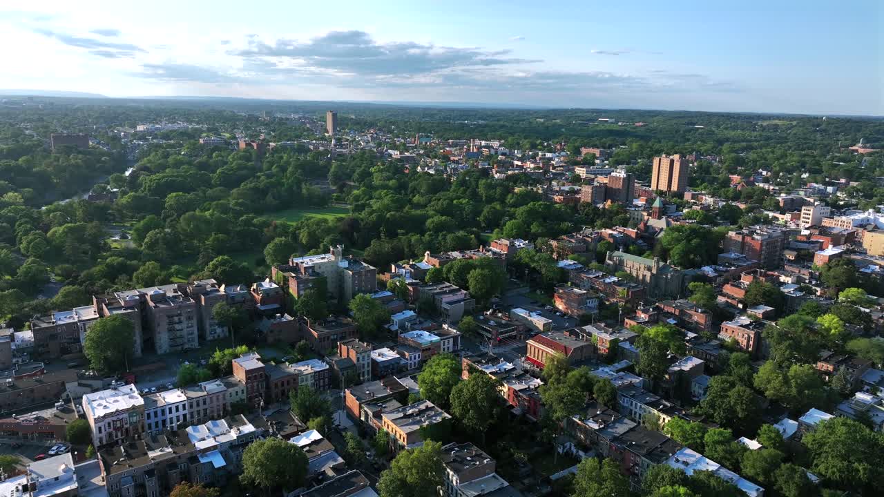 Aerial establishing shot of Albany town in New York at golden sunset. Suburb houses and homes , green park trees and downtown tower blocks. Historic city with red brick facade. Wide shot