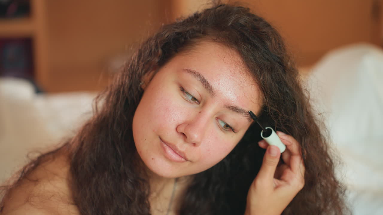 Dawn beauty ritual. Female applies makeup at sunrise. Morning routine involving cosmetics and hair styling. Woman personal grooming session with mirror during early morning hours