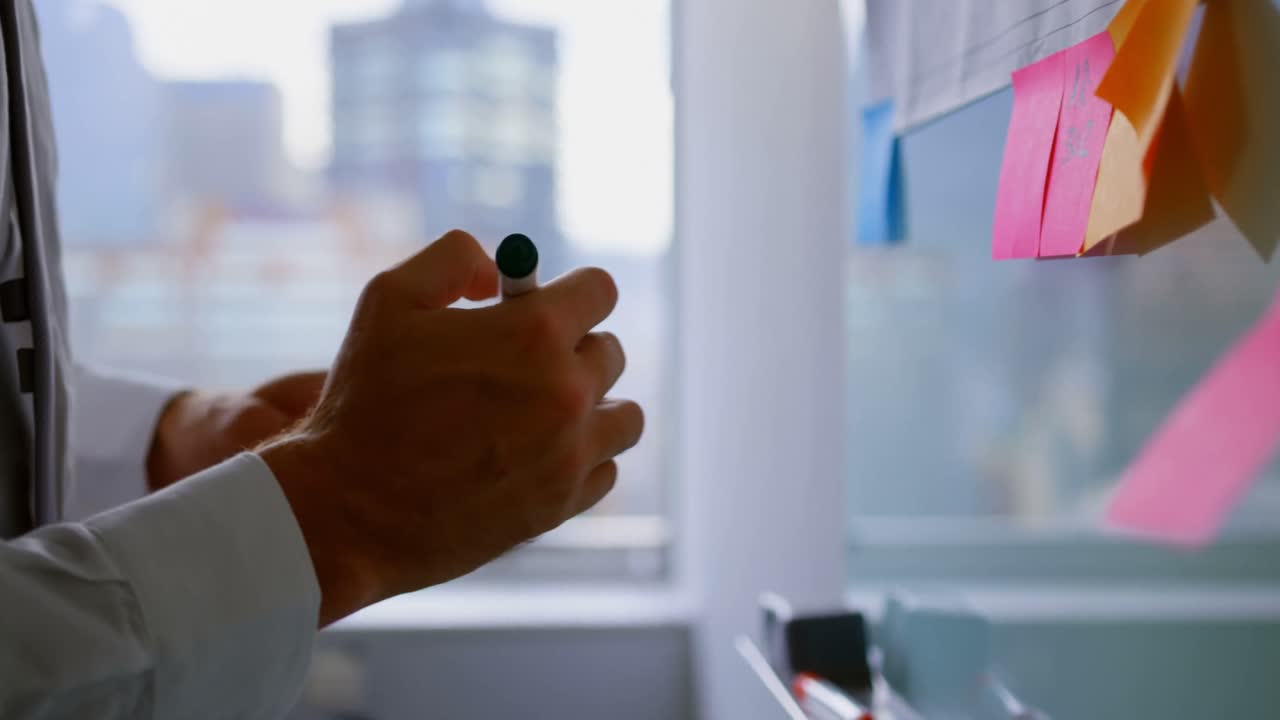 Mezzo busto di giovane dirigente caucasico che lavora con un post-it in un ufficio moderno 4k