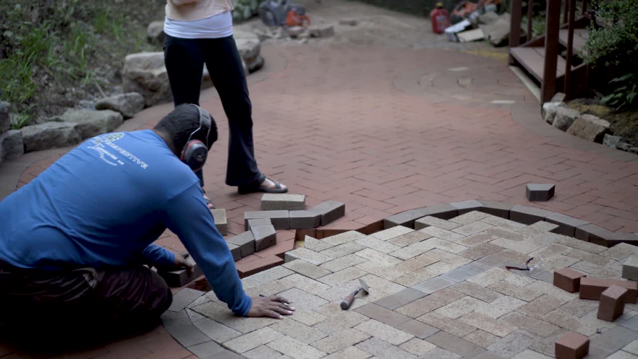 Bricklayer Installing Pavers in a Circular Herringbone Pattern