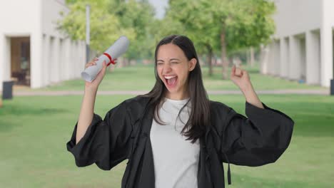 una chica feliz de la universidad india completa su graduación y lanza el sombrero en el aire