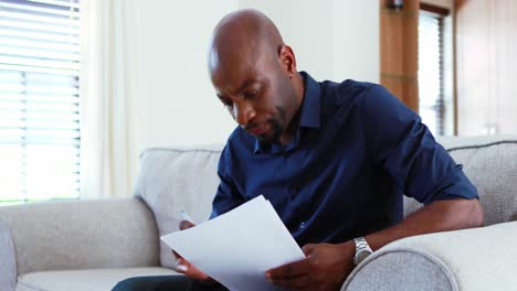 man calculating invoices on mobile phone in living room 4k