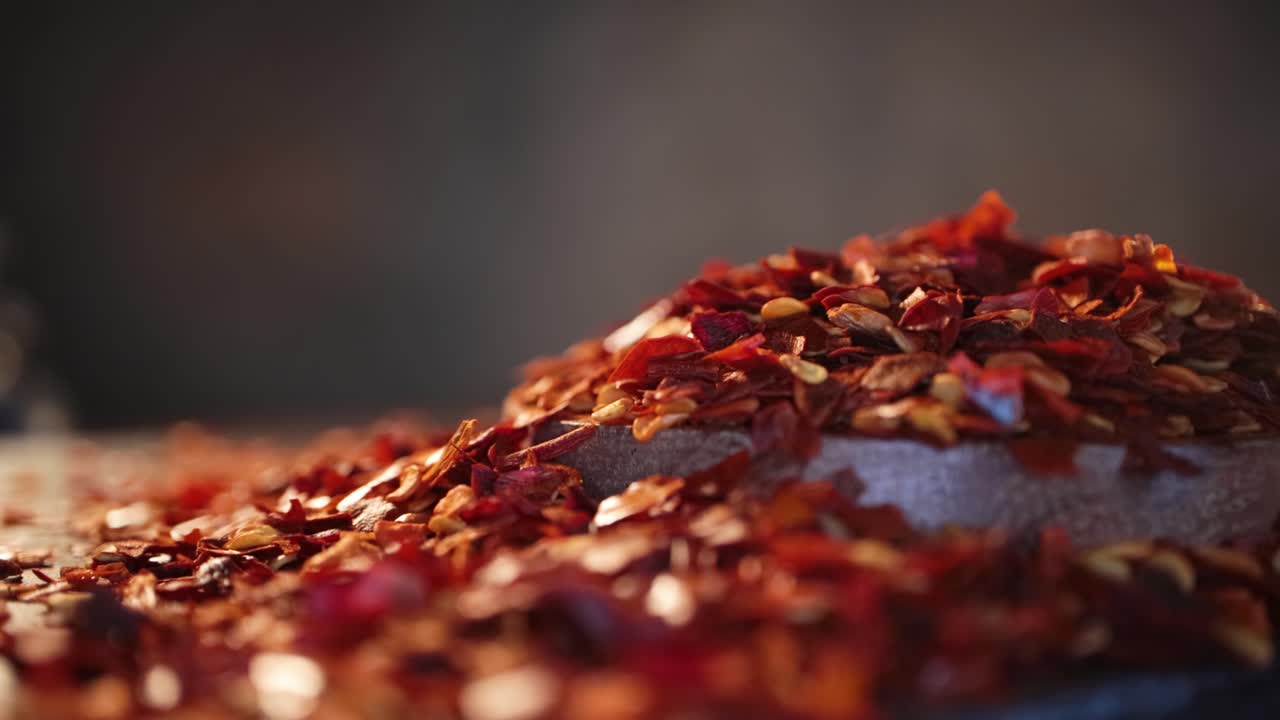 Flakes of red hot chili pepper in wooden spoon closeup on a kitchen table.