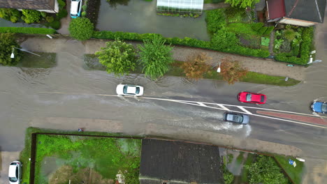 aerial view of cars driving through a heavily flooded residential street after heavy rain