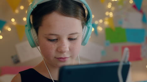 cute little girl using tablet computer listening to music wearing headphones enjoying online entertainment child having fun with portable touchscreen device at home