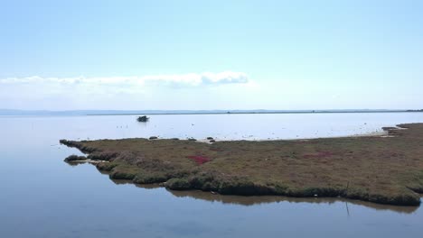 Forward moving drone shot over a patch of land towards a fishing shack in the ocean close to Axios river in Thessaloniki-Northern Greece