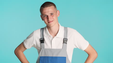 young man in builder uniform posing with arms on hips