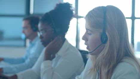 diverse call center workers consulting each other and talking with their headsets