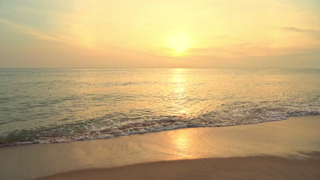 Serene-tropical-sunset-sunrise-scenery,-calm-sea-water-and-empty-sandy-beach-and-orange-sun-on-horizon,-full-frame