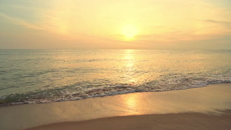 Sereno-Paisaje-Tropical-Del-Amanecer,-Agua-De-Mar-Tranquila-Y-Playa-De-Arena-Vacía-Y-Sol-Naranja-En-El-Horizonte,-Fotograma-Completo