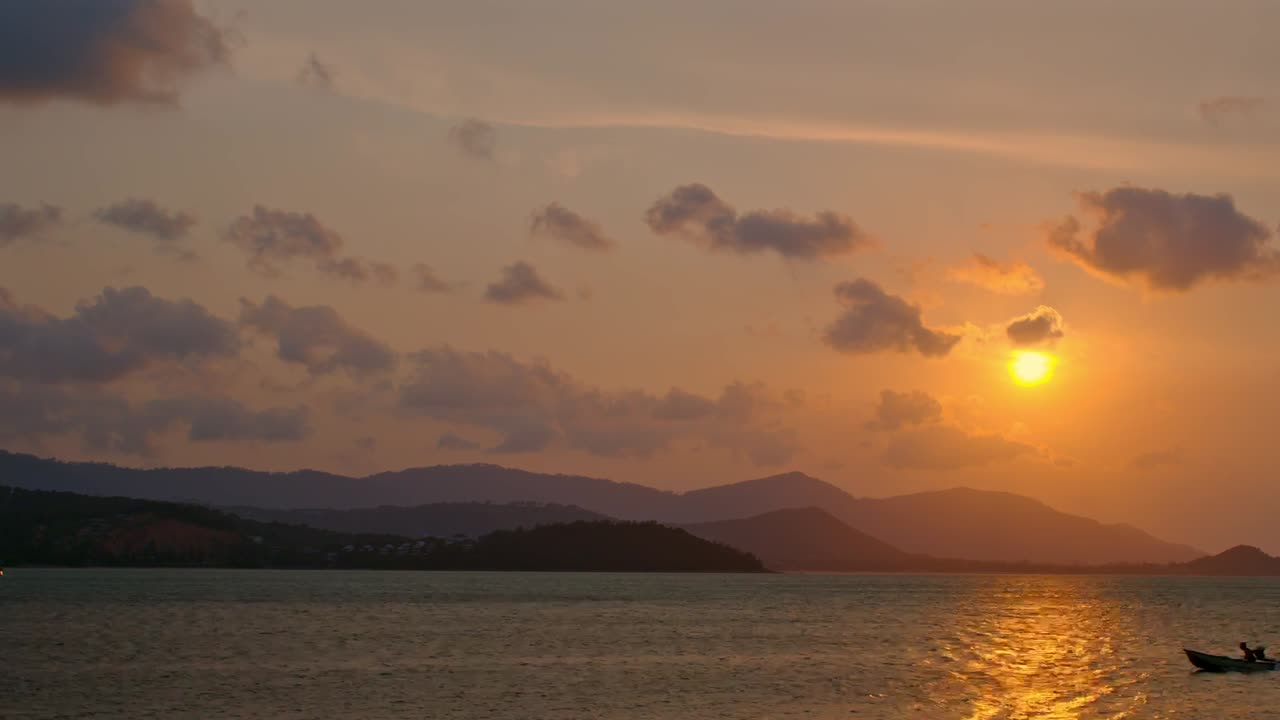 Sunset over the ocean with a small boat