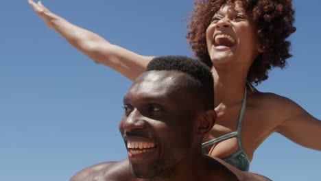 abstract shapes over vibes text over african american man giving his wife a piggyback ride at beach