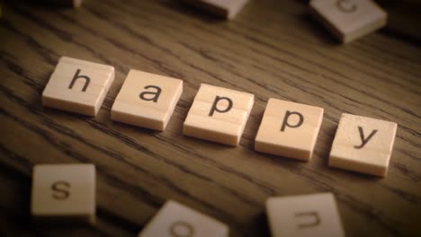 wooden tiles spell the word happy as the camera pans across a rustic wooden surface with warm cinematic lighting.
