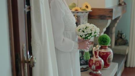 Bride in white dress with a small white bouquet near vintage vases and sunflowers