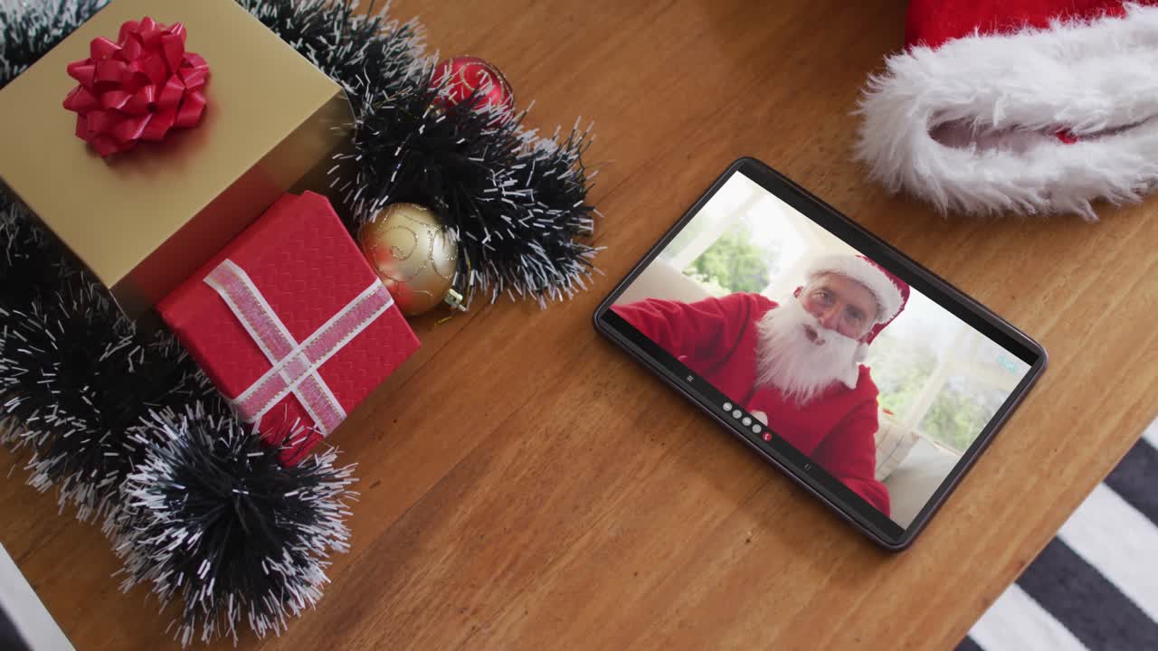 hombre caucásico sonriente vestido con disfraz de santa en una videollamada de navidad en una tableta