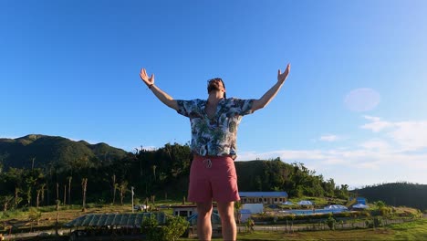 man standing with two hands raised up in the air backlit with dazzling sun. - close up