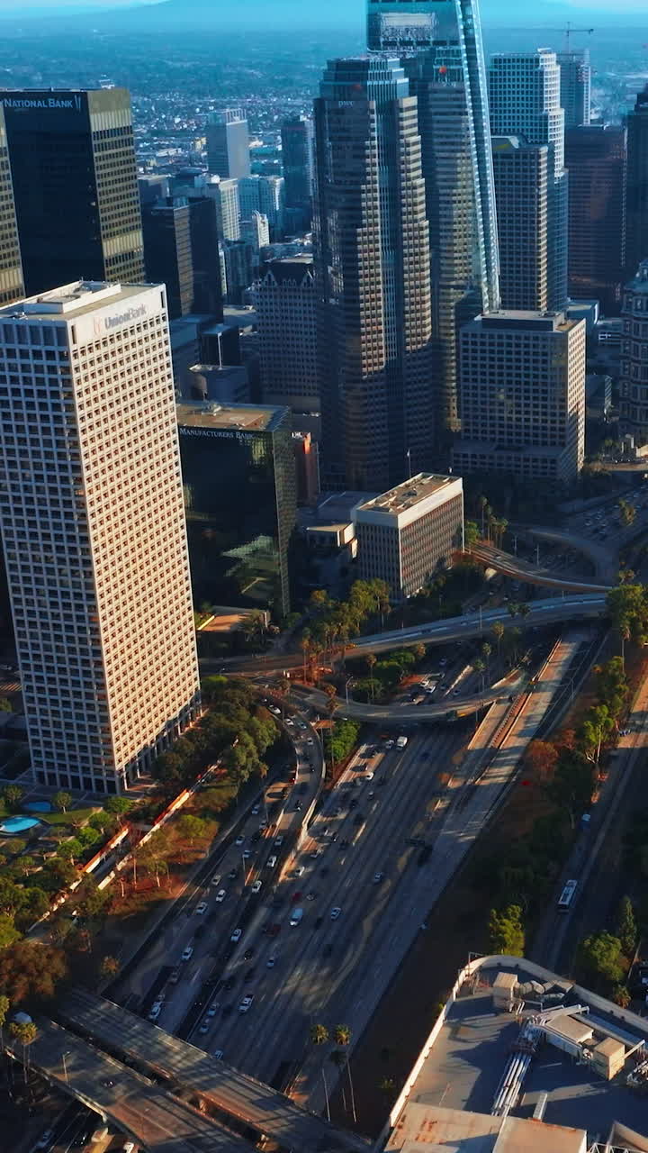 Complicated road systems and junctions between the stunning skyscrapers. Crazy traffic in the downtown of Los Angeles. Aerial view. Vertical video