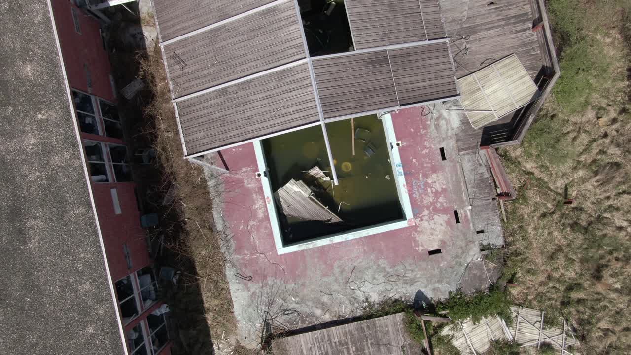 하향식 공중 드론 영상이 상승하여 버려진 수영장과 호텔을 뒤집습니다.