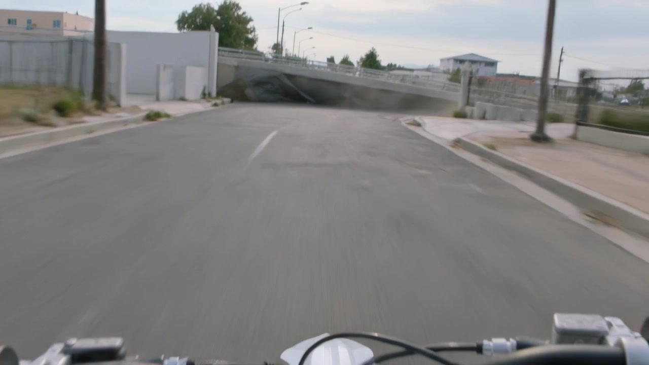 Avvicinandosi a un ostacolo, un ciclista sterza il manubrio a destra per evitare un mucchio di teloni sotto un cavalcavia.