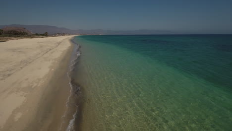 Hohe-Luftdrohne-Fliegt-über-Aufnahmen-Des-Strandes-Mit-Grünem-Smaragdgrünem-Ozeanwasser-Mit-Rauschenden-Wellen-In-Cabo-San-Lucas,-Mexiko