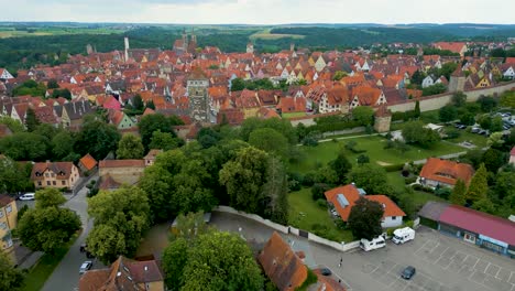 4k aerial drone video of the röderturm tower and turm und stadtmauerweg park outside the gate of the walled city of rothenburg ob der tauber, germany