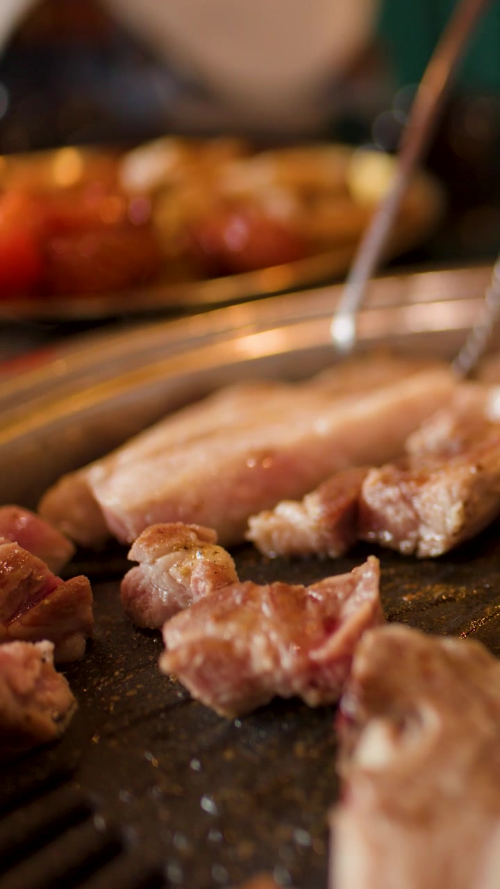 Close-up daging panggang yang dipotong dengan gunting di atas panggangan meja berasap, pencahayaan hangat.