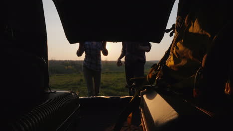 arrival at the place of vacation couple unloads bags from the trunk of a car