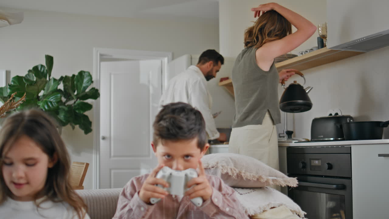 Happy parents cooking breakfast at home closeup. Two kids playing video game