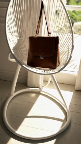 brown leather briefcase on modern white chair with sunlight and shadows