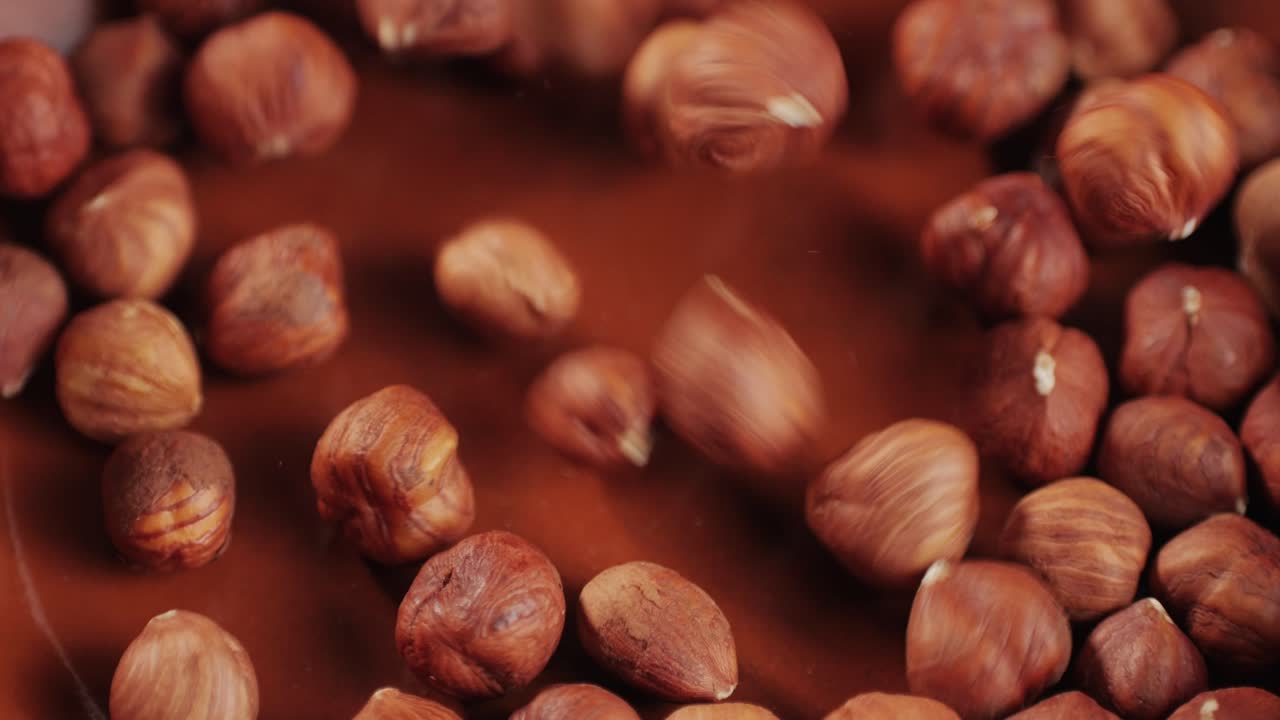 Peeled hazelnut falling down on red plate close-up macro. Hazelnuts without shell. Product rich in minerals and vitamins. Healthy snacks. High quality 4k footage