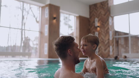 preschooler boy and his dad are swimming in pool happy child and father in wellness center for family