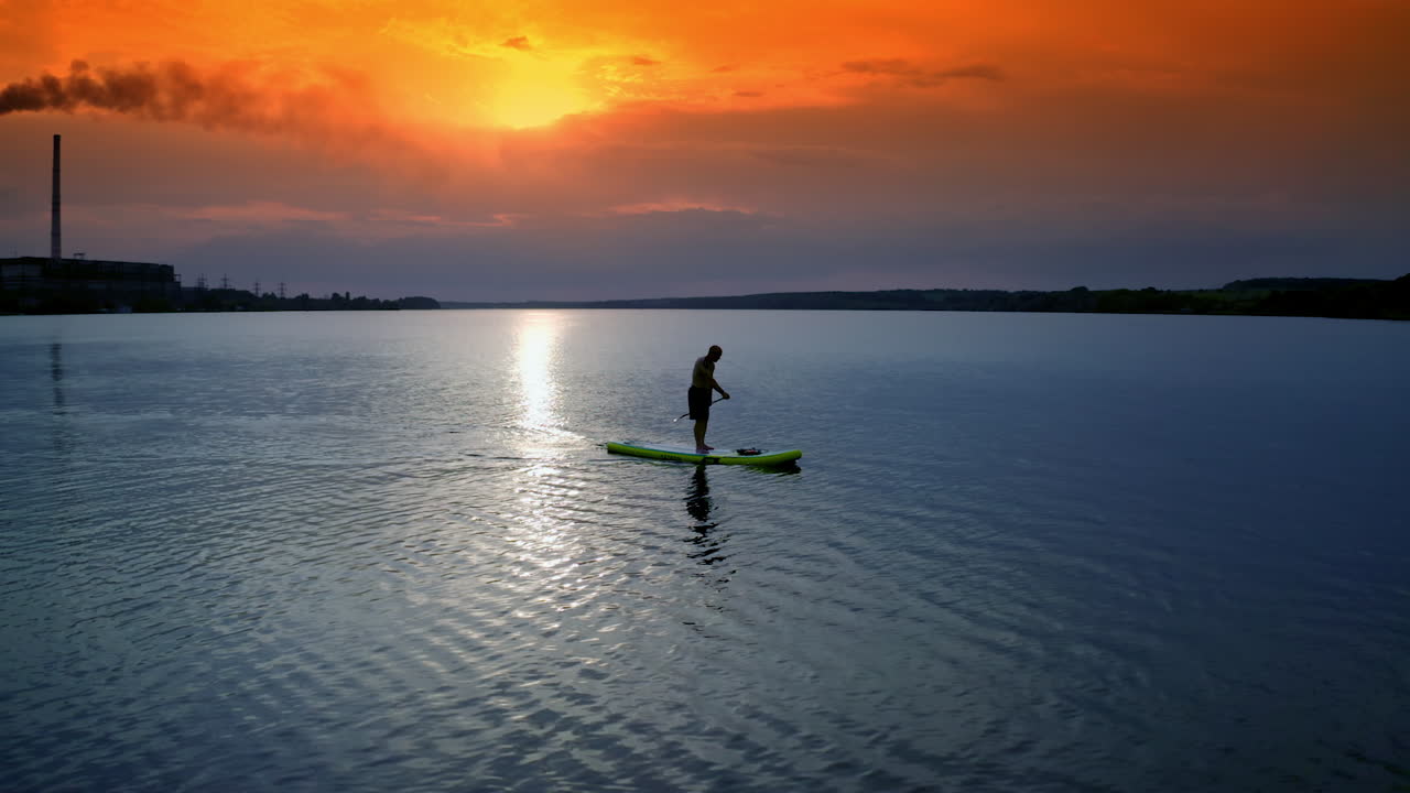 Pria mendayung di papan SUP. Pemandangan indah pria bersantai di air dengan papan SUP.
