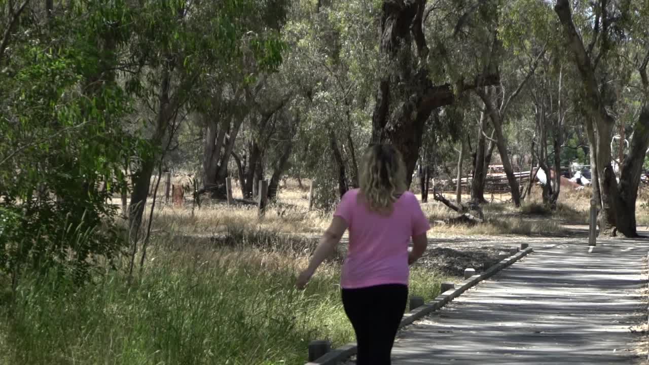 Outdoor nature blonde woman walking in nature along bridge