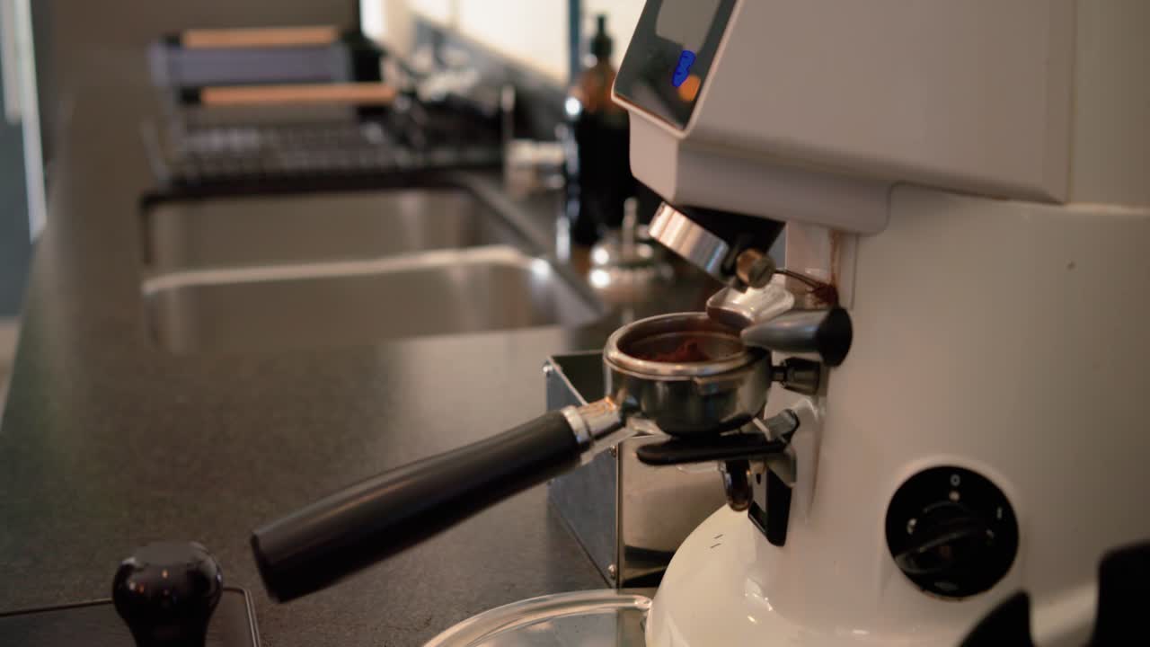 Donna che inserisce un portafiltro in un macinino in cucina, riempiendolo di caffè macinato per la preparazione, spazio per il testo