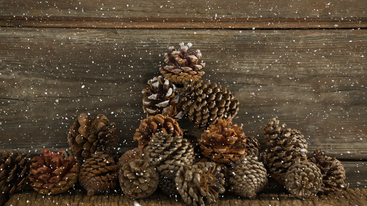 nieve cayendo sobre múltiples conos de pino en la superficie de madera