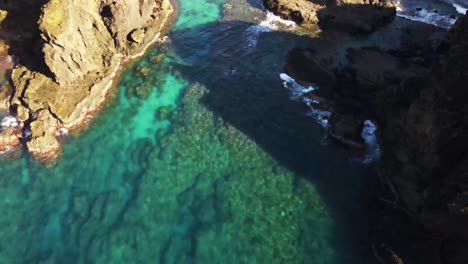 Reveal-of-crystal-blue-waters-and-rocky-reef-breaking-onto-seashore-of-pacific-island