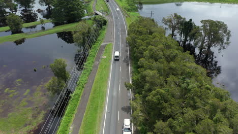 4K-Drohnenaufnahme-Von-Autos,-Die-Auf-Einer-Kleinen-Straße-Neben-Einer-Großen-Flut-In-Byron-Bay,-Australien,-Fahren