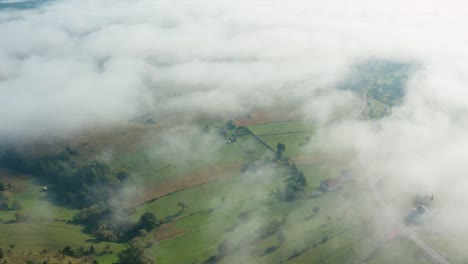 toma aérea mirando hacia abajo a través de las nubes hacia el paisaje rural debajo
