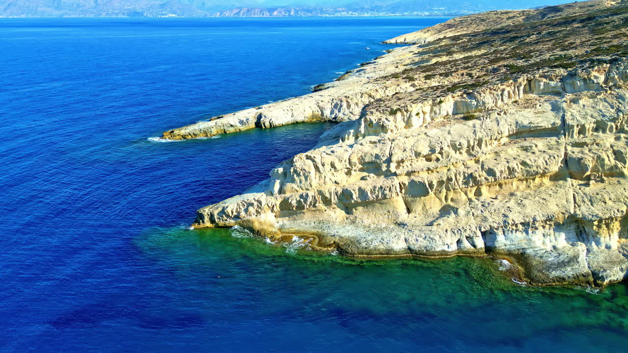 Rocky coastal cliffs with crystal clear blue waters stretching along the rugged shoreline