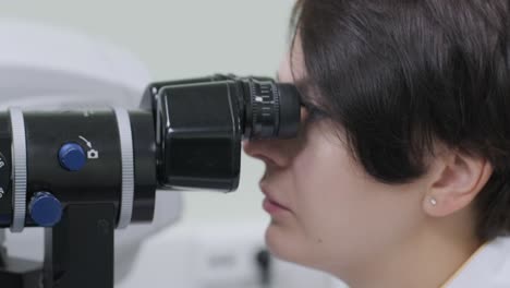 la mujer está viendo a través del oftalmoscopio en los ojos del paciente en la clínica oftalmológica. inspección profesional de la visión