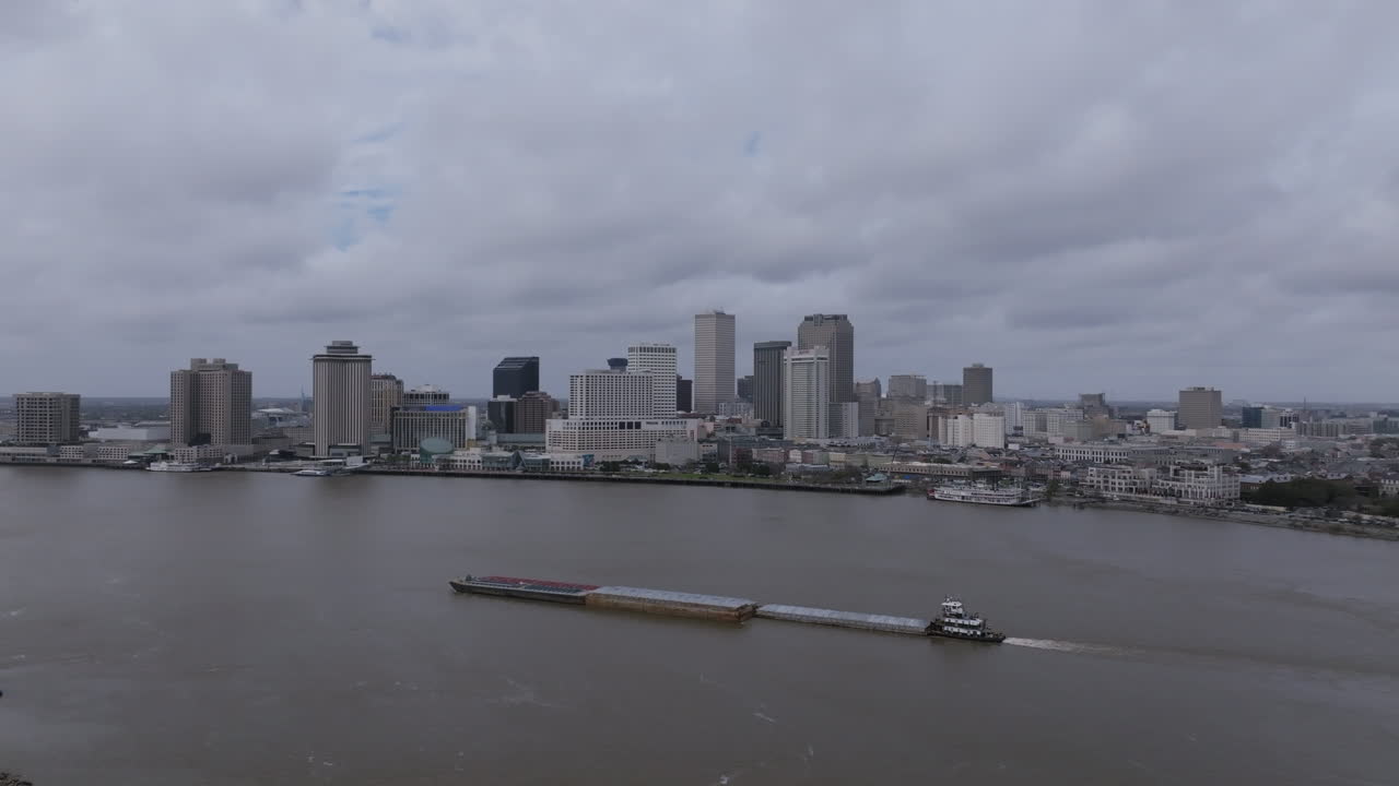 imágenes aéreas volando hacia atrás lejos de una gran barcaza que está navegando por el río mississippi con el centro de nueva orleans en el fondo